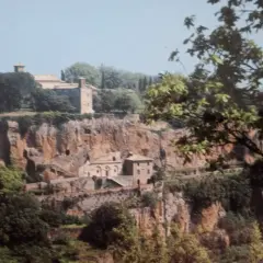 Antico complesso monastico di Santa Maria ad Rupes, incastonato nella roccia, con edifici in pietra e vegetazione rigogliosa.