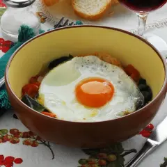 Uovo fritto su verdure e pane, accompagnato da un bicchiere di vino crudo Acquapendente.