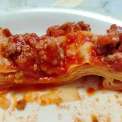 Fetta di lasagna con ragù, strati di pasta e sugo rosso. Non sono fregnacce, ma un piatto delizioso!