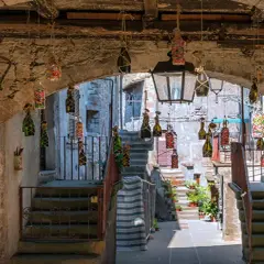 Un vicolo suggestivo a Vitorchiano, Viterbo, con bottiglie decorate appese e un'icona sacra.