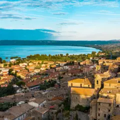 Borghi da visitare vicino Bolsena: vista aerea di un antico castello e case con tetti in tegole rosse, con il lago sullo sfondo.