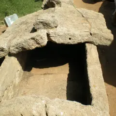 Antica tomba scavata nella roccia, esempio di cosa sono le necropoli. Un riflettore è appoggiato sul bordo.
