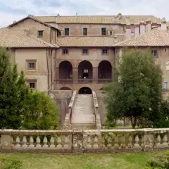 Villa Giustiniani Bassano Romano: imponente residenza storica circondata da verde, con scalinata e loggiato ad archi.