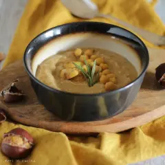 Una ciotola di zuppa ceci e castagne viterbese, guarnita con ceci, castagne e rosmarino, circondata da castagne.
