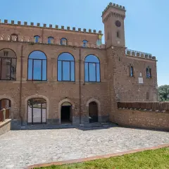 Il **Palazzo Doebbing**, con la sua torre dell'orologio e le ampie finestre ad arco, si affaccia su un cortile lastricato sotto un cielo azzurro.