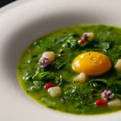 Un piatto verde brillante con un tuorlo d'uovo dorato, erbe fresche e fiori viola, un'interpretazione moderna dei piatti tipici viterbesi.