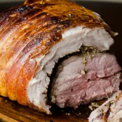 Porchetta viterbese succulenta, con crosta dorata e carne rosata, pronta per essere gustata.