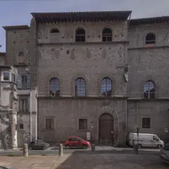 Antico palazzo chigi viterbo con finestre ad arco e un portone in legno. Auto parcheggiate nella piazza antistante.