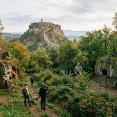 Sentiero verso Civita di Bagnoregio, una città fantasma nel Lazio, tra antiche tombe etrusche e sculture enigmatiche.