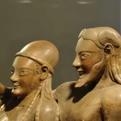 Coppia di statue in terracotta, parte di corredi funerari etruschi. Un uomo indica qualcosa, la donna lo guarda con un sorriso.