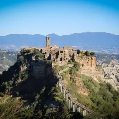 Antica città arroccata su una rupe, con un ponte pedonale che conduce al borgo. Paesaggio mozzafiato di Calcata e dintorni.