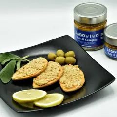 Bruschette con paté di coregone bolsena, olive verdi, limone e salvia. Due vasetti di paté di coregone in primo piano.