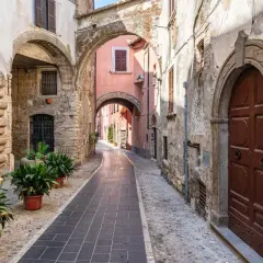 Un vicolo suggestivo a Orte, Viterbo, con archi in pietra, porte antiche e piante verdi.