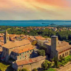 Panoramica di un borgo italiano con un lago sullo sfondo. Scopri cosa vedere a Valentano: un incantevole paesaggio tra storia e natura.