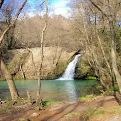 Cascata della mola di Oriolo, con acque turchesi e alberi spogli che incorniciano la scena.