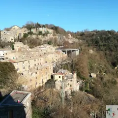 Borgo antico su una collina, con case in pietra e tetti rossi. La **Calcata storia** si svela in questo panorama.