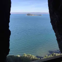 Vista da una grotta sul lago, con un'isola verde in lontananza. Il **monte Bisenzio** si staglia all'orizzonte.