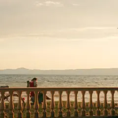Tramonto sulle spiagge del lago di Bolsena. Una persona in sedia a sdraio, biciclette e un albero creano un'atmosfera serena.