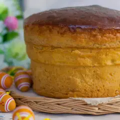 Pizza di Pasqua dolce viterbese, soffice e dorata, circondata da uova colorate e fiori primaverili.