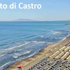 Spiaggia di Montalto di Castro con file ordinate di ombrelloni e lettini, mare azzurro e onde leggere.