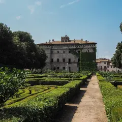Giardini geometrici e un palazzo storico, il castello Ruspoli a Vignanello, sotto un cielo azzurro.