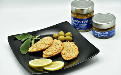 Bruschette con paté di coregone bolsena, olive verdi, limone e salvia. Due vasetti di paté di coregone in primo piano.