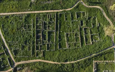 Vista aerea della necropoli centocamere, con rovine antiche immerse nel verde e sentieri che le attraversano.