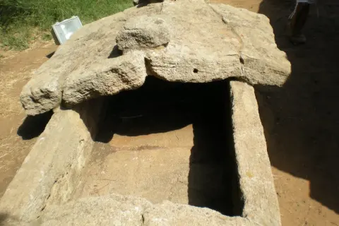 Antica tomba scavata nella roccia, esempio di cosa sono le necropoli. Un riflettore è appoggiato sul bordo.