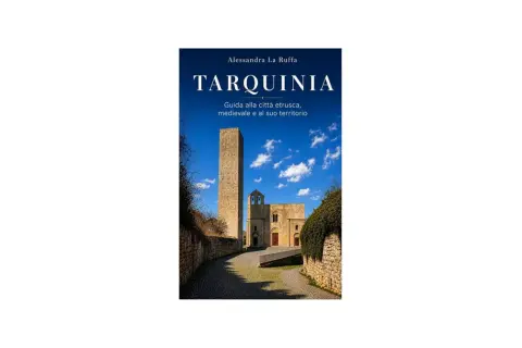 Copertina libro "Tarquinia: Guida alla città etrusca, medievale e al suo territorio". Torre medievale e chiesa sotto un cielo azzurro.