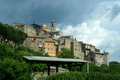 Antico borgo di **Tuscie Vetralla**, con case in pietra aggrappate alla collina sotto un cielo nuvoloso.