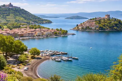 Marta al lago di Bolsena, con borghi pittoreschi, un porto turistico e colline verdi.