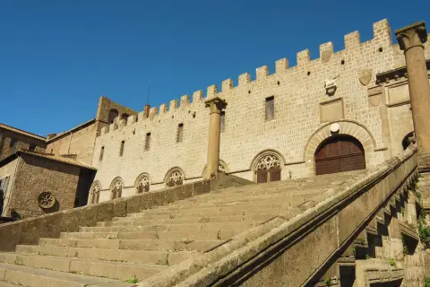 Imponente scalinata conduce al Palazzo dei Papi, parte del duomo di Viterbo, con finestre gotiche e merlature.