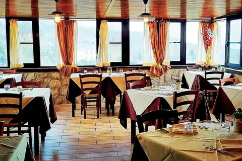 Interno di un'antica cantina a Caprarola, con tavoli apparecchiati e vista panoramica.