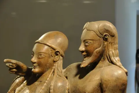 Coppia di statue in terracotta, parte di corredi funerari etruschi. Un uomo indica qualcosa, la donna lo guarda con un sorriso.