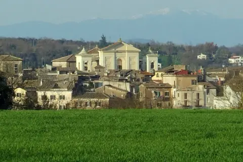 Paesaggio di Gallese, borgo vicino Viterbo, con case e una chiesa imponente, sullo sfondo montagne.