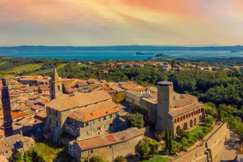 Panoramica di un borgo italiano con un lago sullo sfondo. Scopri cosa vedere a Valentano: un incantevole paesaggio tra storia e natura.