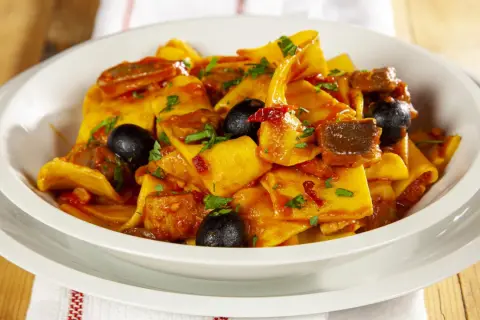 Piatto di fregnacce con sugo di pomodoro, olive nere e carne. Una deliziosa ricetta da provare subito!