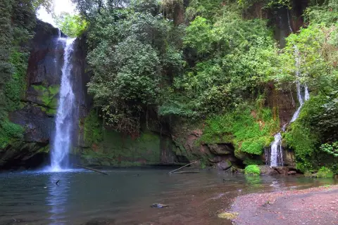 La cascata del picchio scende maestosa tra rocce ricoperte di muschio e vegetazione lussureggiante, creando un'oasi di pace.