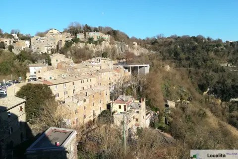 Borgo antico su una collina, con case in pietra e tetti rossi. La **Calcata storia** si svela in questo panorama.