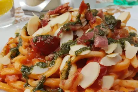 Pasta con pomodoro, pesto, mandorle e pancetta croccante, un piatto da gustare all'enoteca Civita.