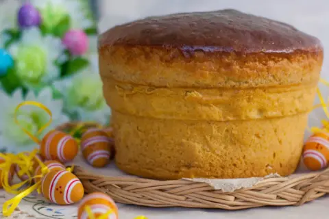 Pizza di Pasqua dolce viterbese, soffice e dorata, circondata da uova colorate e fiori primaverili.