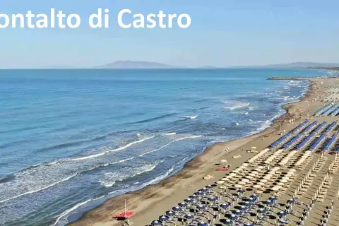 Spiaggia di Montalto di Castro con file ordinate di ombrelloni e lettini, mare azzurro e onde leggere.