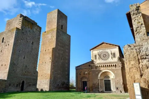 Le chiese di Tuscania, con le loro torri medievali e la facciata romanica, si stagliano contro un cielo azzurro.