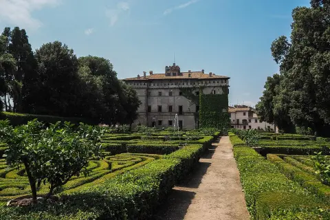 Giardini geometrici e un palazzo storico, il castello Ruspoli a Vignanello, sotto un cielo azzurro.