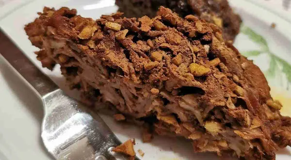 Fetta di torta con strati di pasta e noci, ricoperta di cacao. Un dolce invitante, perfetto per chi ama i maccheroni dolci con le noci.