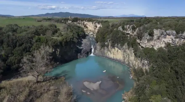 Cascata del Pelago, un gioiello naturale dove si trova Vulci, con acque turchesi che si infrangono tra rocce e vegetazione lussureggiante.