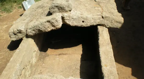 Antica tomba scavata nella roccia, esempio di cosa sono le necropoli. Un riflettore è appoggiato sul bordo.