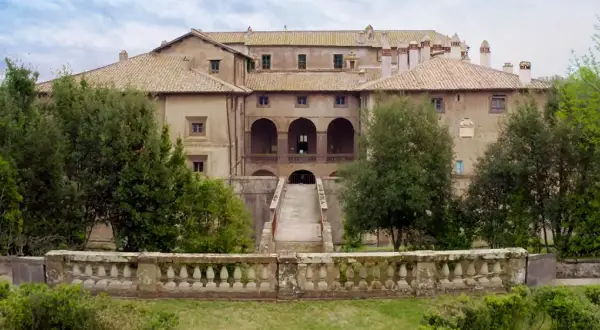 Villa Giustiniani Bassano Romano: imponente residenza storica circondata da verde, con scalinata e loggiato ad archi.