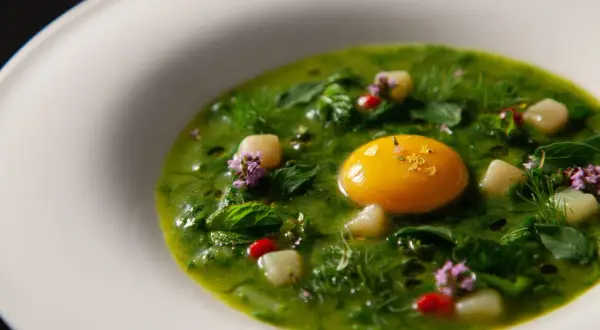 Un piatto verde brillante con un tuorlo d'uovo dorato, erbe fresche e fiori viola, un'interpretazione moderna dei piatti tipici viterbesi.