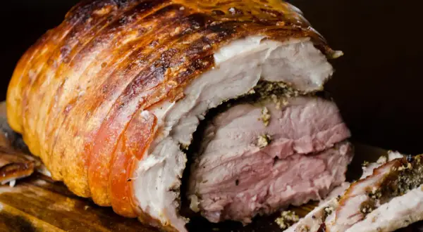 Porchetta viterbese succulenta, con crosta dorata e carne rosata, pronta per essere gustata.